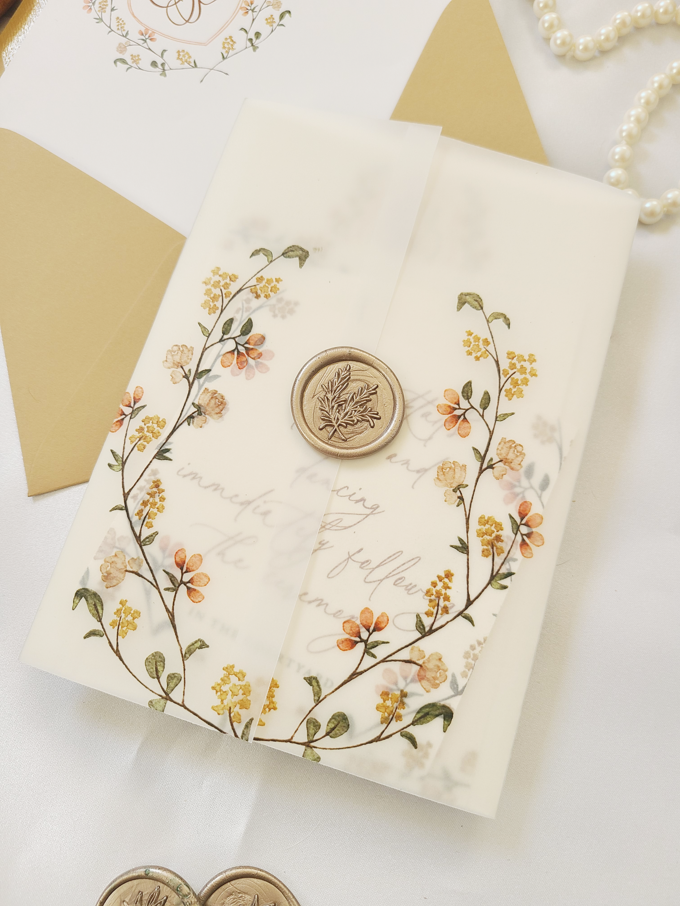 the tatiana wedding invitation suite with warm flowers around a classic wedding monogram crest